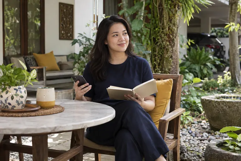 Pelanggan dengan telefon dan buku di meja beranda